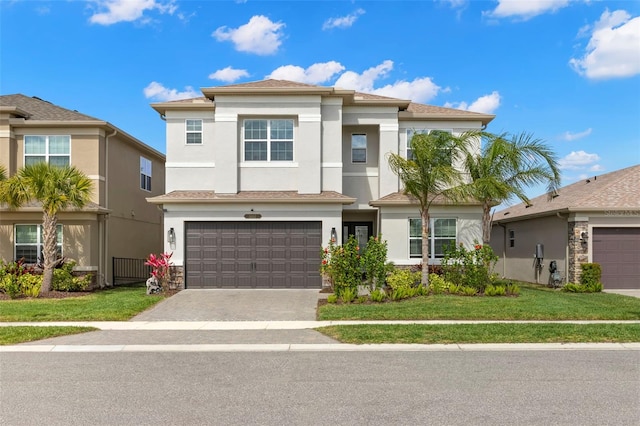 view of front facade with a garage, a front yard, decorative driveway, and stucco siding