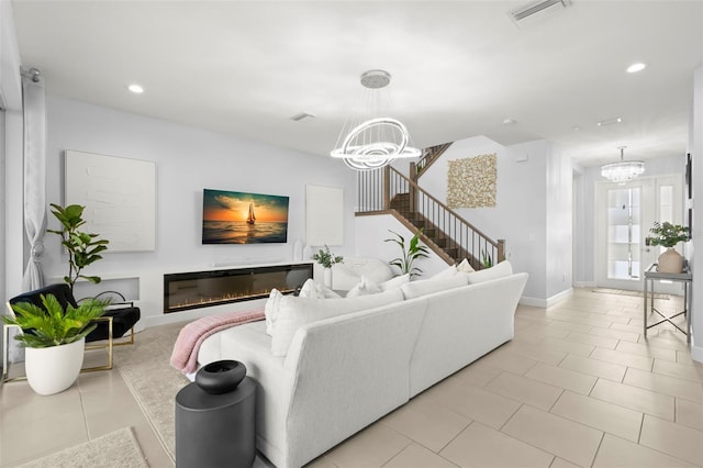 living room with a glass covered fireplace, visible vents, a notable chandelier, and stairway