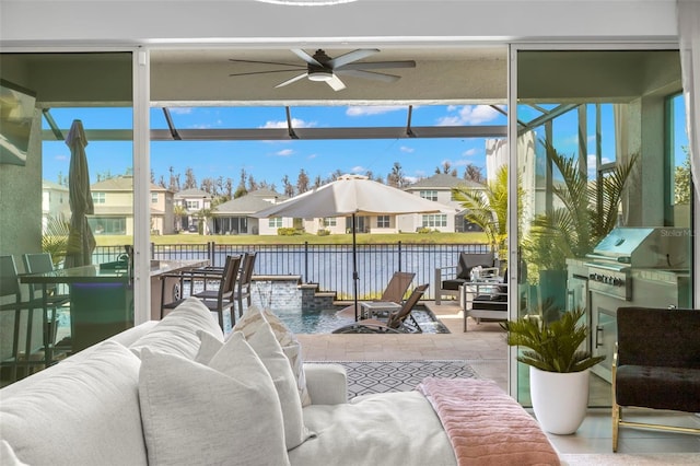 sunroom / solarium featuring a water view, a residential view, and a ceiling fan