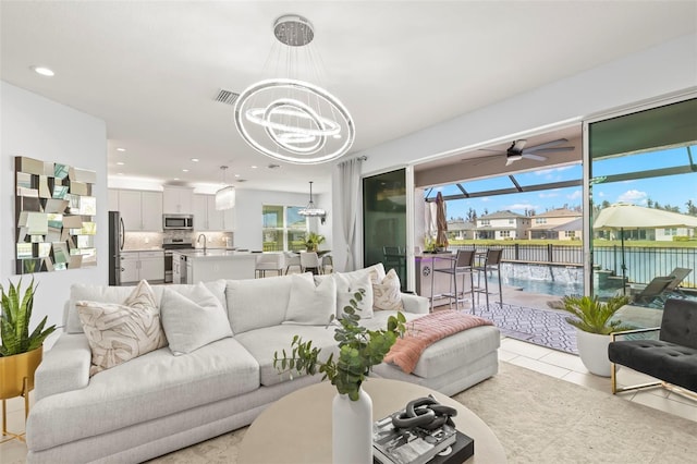 living area featuring recessed lighting, light tile patterned flooring, visible vents, and ceiling fan with notable chandelier