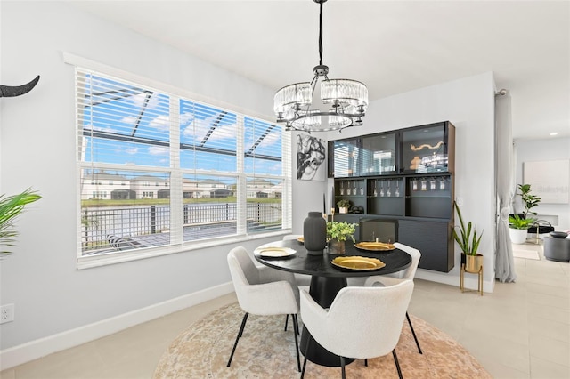 dining area featuring a chandelier, tile patterned flooring, and baseboards