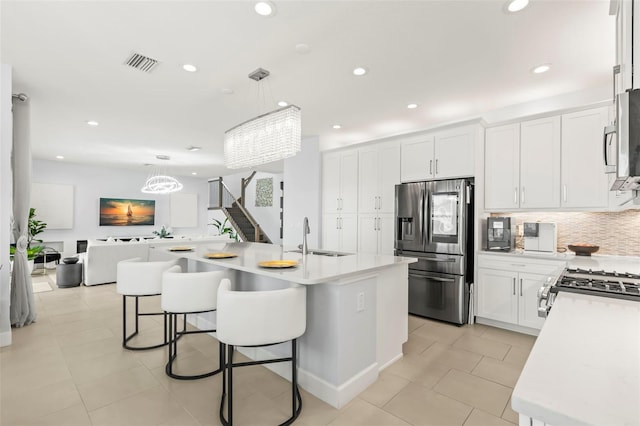 kitchen featuring tasteful backsplash, visible vents, white cabinets, stainless steel appliances, and a sink