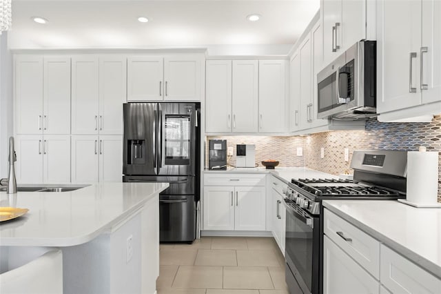 kitchen featuring appliances with stainless steel finishes, a sink, light countertops, white cabinetry, and backsplash