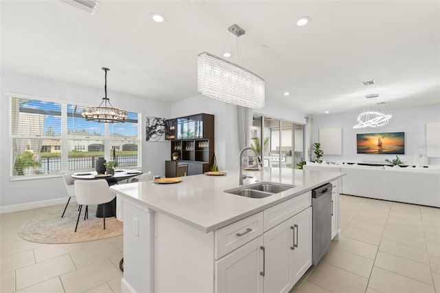 kitchen with a notable chandelier, a sink, open floor plan, light countertops, and stainless steel dishwasher