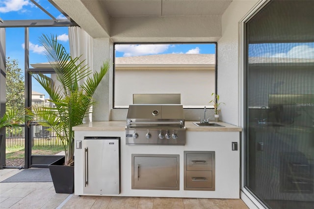 view of patio / terrace with a lanai, exterior kitchen, a sink, and area for grilling