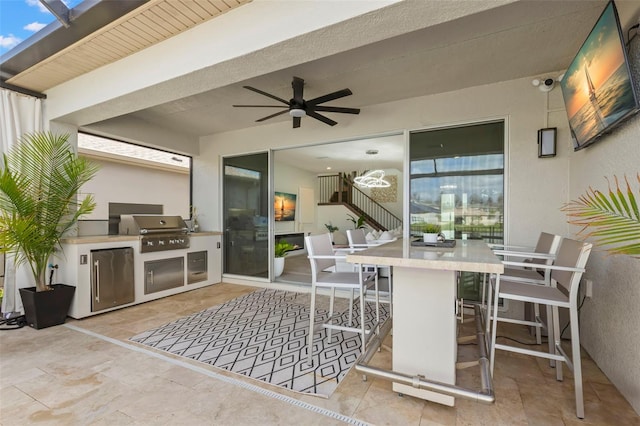 view of patio with outdoor wet bar, an outdoor kitchen, a ceiling fan, and area for grilling