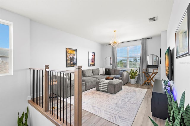 living room featuring a chandelier, light wood finished floors, and visible vents