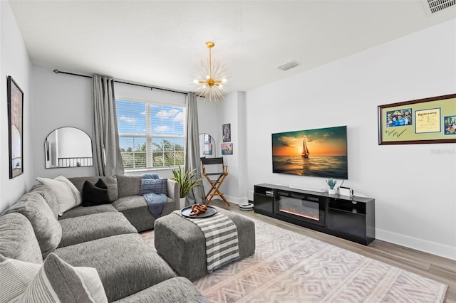 living area with visible vents, a notable chandelier, baseboards, and wood finished floors