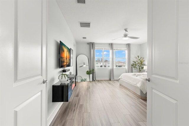 bedroom with baseboards, ceiling fan, visible vents, and wood finished floors