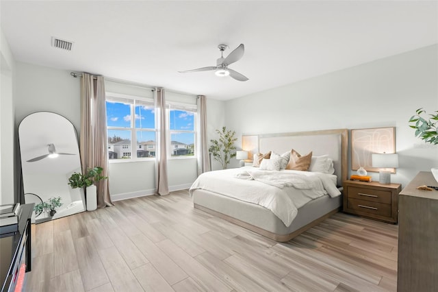 bedroom featuring baseboards, light wood-type flooring, visible vents, and a ceiling fan