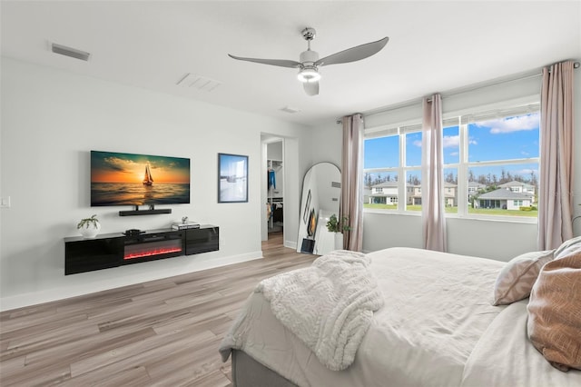 bedroom featuring visible vents, a spacious closet, ceiling fan, wood finished floors, and baseboards