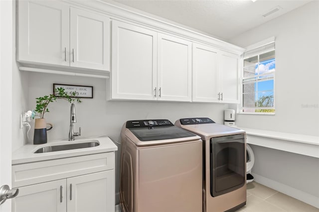 laundry room with light tile patterned floors, cabinet space, visible vents, a sink, and separate washer and dryer