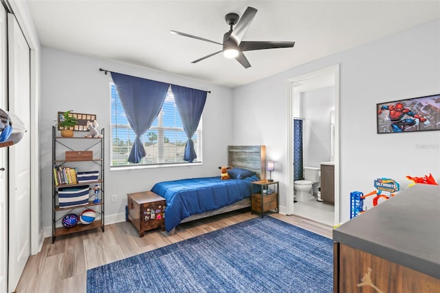 bedroom with a ceiling fan, ensuite bath, baseboards, and wood finished floors