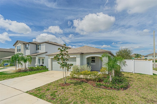 mediterranean / spanish-style home with a garage, driveway, fence, a front lawn, and stucco siding