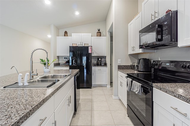 kitchen with light tile patterned floors, white cabinets, vaulted ceiling, a sink, and black appliances