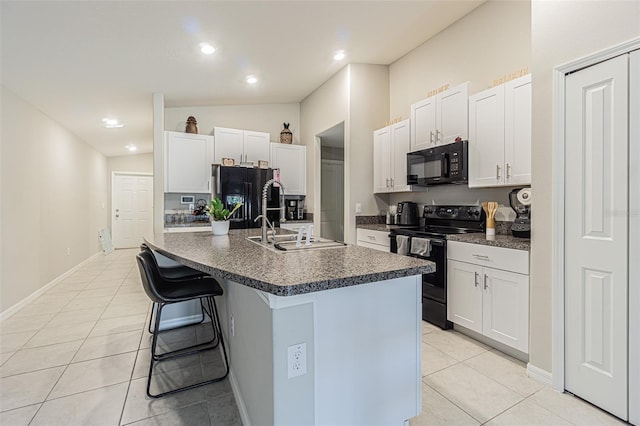 kitchen featuring light tile patterned flooring, a sink, a kitchen breakfast bar, black appliances, and dark countertops