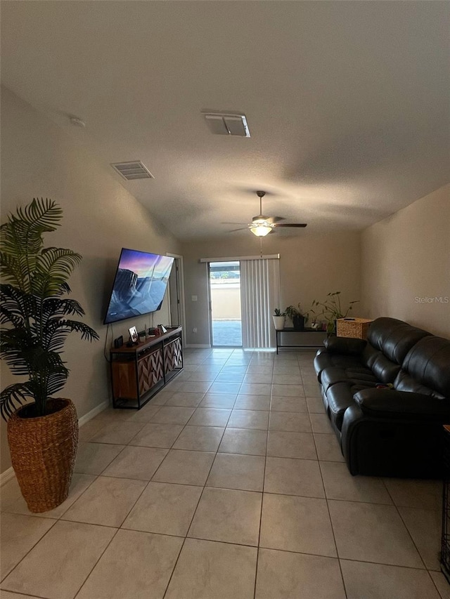 living area with light tile patterned floors, a textured ceiling, visible vents, baseboards, and a ceiling fan