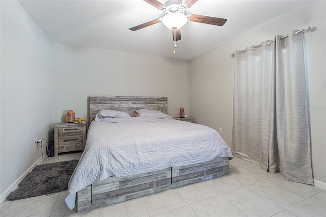 bedroom with a textured ceiling, ceiling fan, tile patterned flooring, and baseboards