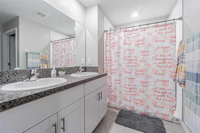 bathroom featuring double vanity, tile patterned flooring, visible vents, and a sink