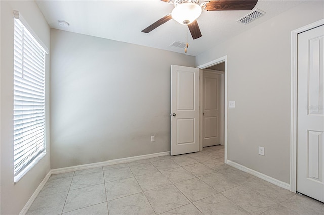 unfurnished bedroom featuring visible vents, baseboards, and multiple windows