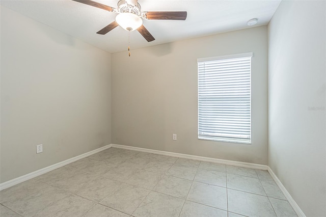 unfurnished room featuring a wealth of natural light, ceiling fan, and baseboards