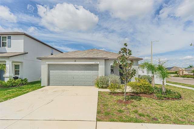 view of front facade with an attached garage, driveway, a front yard, and stucco siding