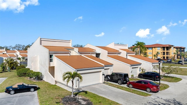 view of front of house featuring a garage, concrete driveway, a residential view, stucco siding, and a front lawn