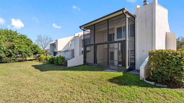 rear view of house featuring a sunroom and a yard