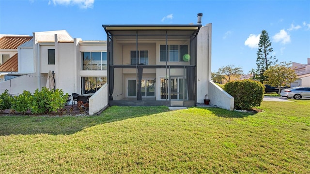 rear view of house with a sunroom, a yard, and stucco siding