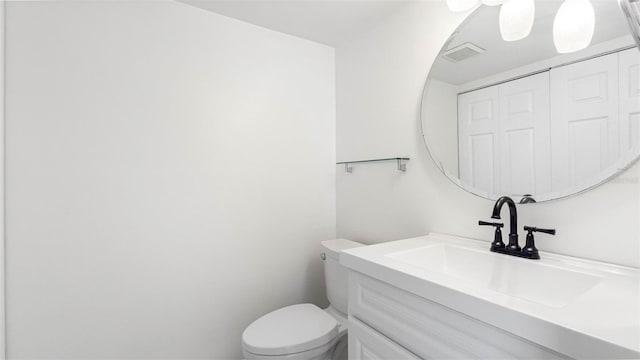 bathroom with toilet, visible vents, and vanity