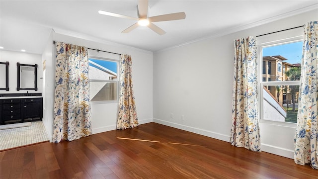 empty room featuring baseboards, wood finished floors, a ceiling fan, and crown molding