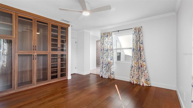 empty room featuring visible vents, ornamental molding, a ceiling fan, wood finished floors, and baseboards