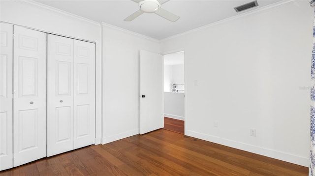 unfurnished bedroom with baseboards, visible vents, dark wood finished floors, crown molding, and a closet