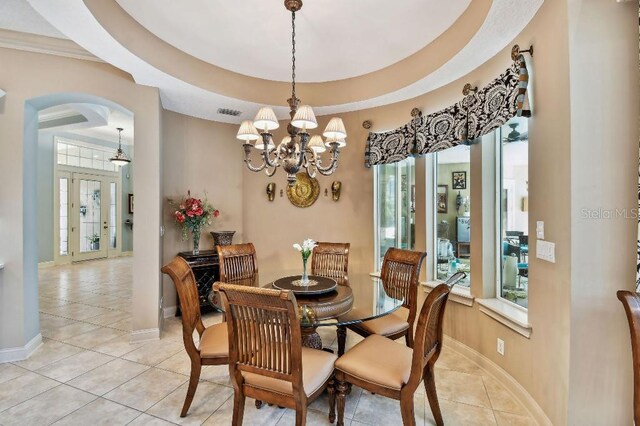 dining area with a raised ceiling, light tile patterned floors, a healthy amount of sunlight, and arched walkways