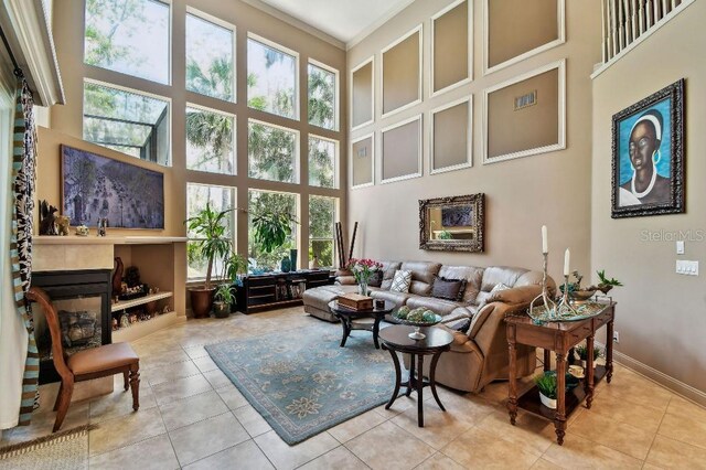 tiled living room featuring baseboards, a high ceiling, and a glass covered fireplace