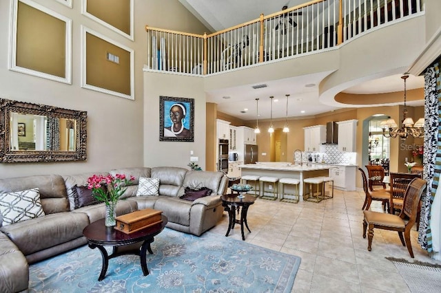 living area featuring an inviting chandelier, a high ceiling, light tile patterned flooring, and visible vents