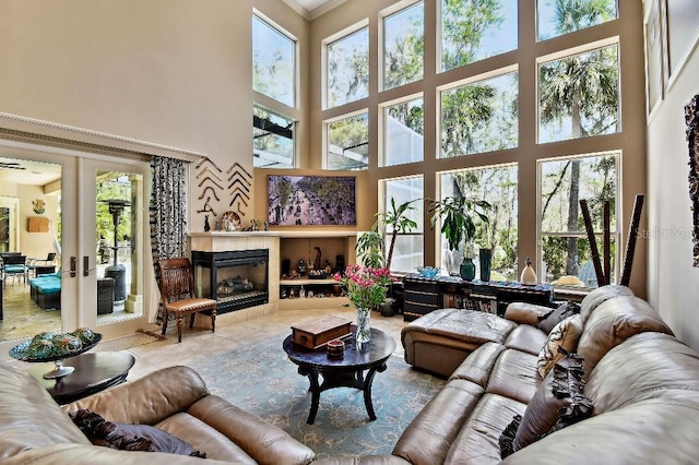 tiled living room with plenty of natural light, a tile fireplace, a high ceiling, and french doors