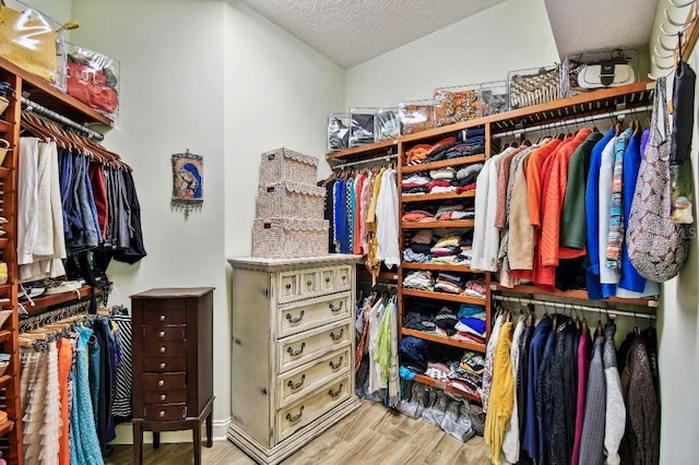 walk in closet with wood finished floors and vaulted ceiling