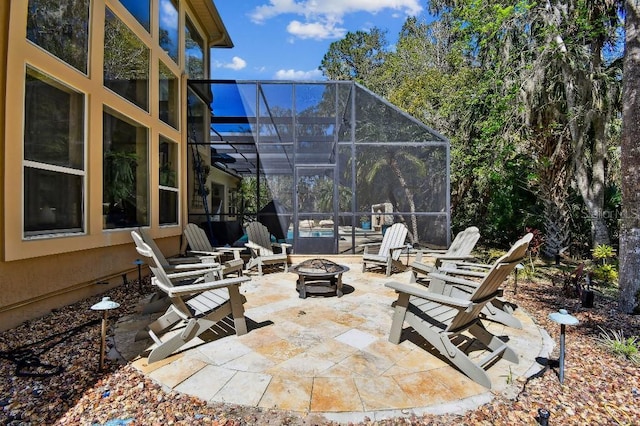 view of patio / terrace featuring glass enclosure, a pool, and an outdoor fire pit