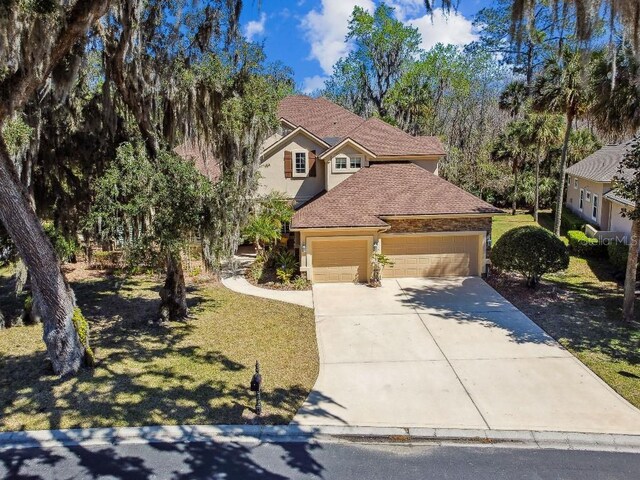 view of front of house with a front lawn, an attached garage, driveway, and stucco siding