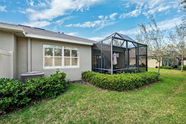 1467 Twin Villas Way, Dunedin, FL 34698 - rear view of house with stucco siding, central AC unit, a yard, and glass enclosure