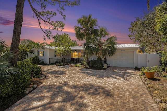 ranch-style home with a garage, a fenced front yard, decorative driveway, and stucco siding