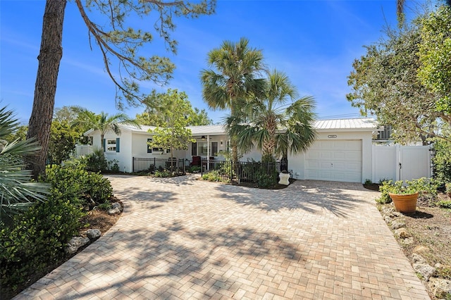 view of front of house featuring a fenced front yard, an attached garage, a gate, decorative driveway, and stucco siding