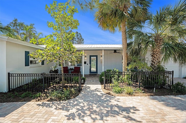 exterior space featuring covered porch, a fenced front yard, and metal roof