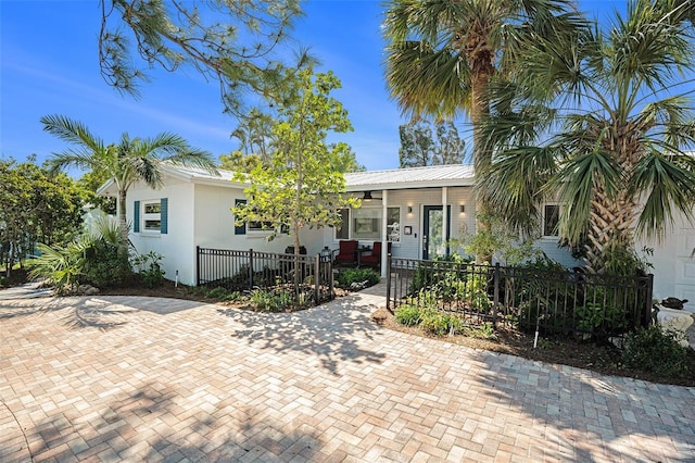 view of front of home featuring a fenced front yard, metal roof, and stucco siding