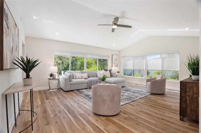 living area featuring a healthy amount of sunlight, light wood-style floors, baseboards, and vaulted ceiling