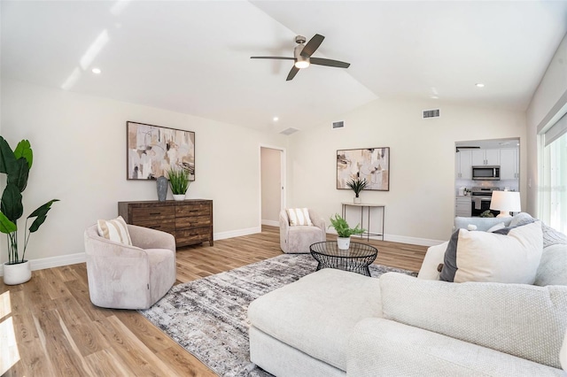 living room featuring light wood-style flooring, visible vents, vaulted ceiling, and baseboards