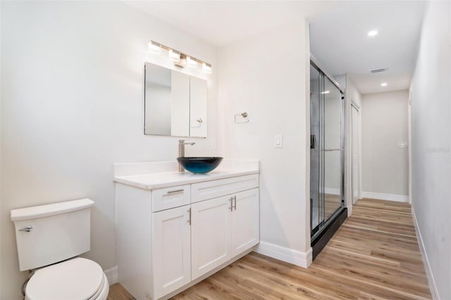 bathroom featuring toilet, wood finished floors, vanity, baseboards, and a shower stall