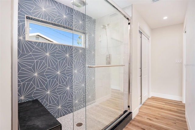 bathroom featuring baseboards, a tile shower, and wood finished floors