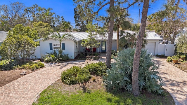 ranch-style house featuring a garage, decorative driveway, fence, and stucco siding